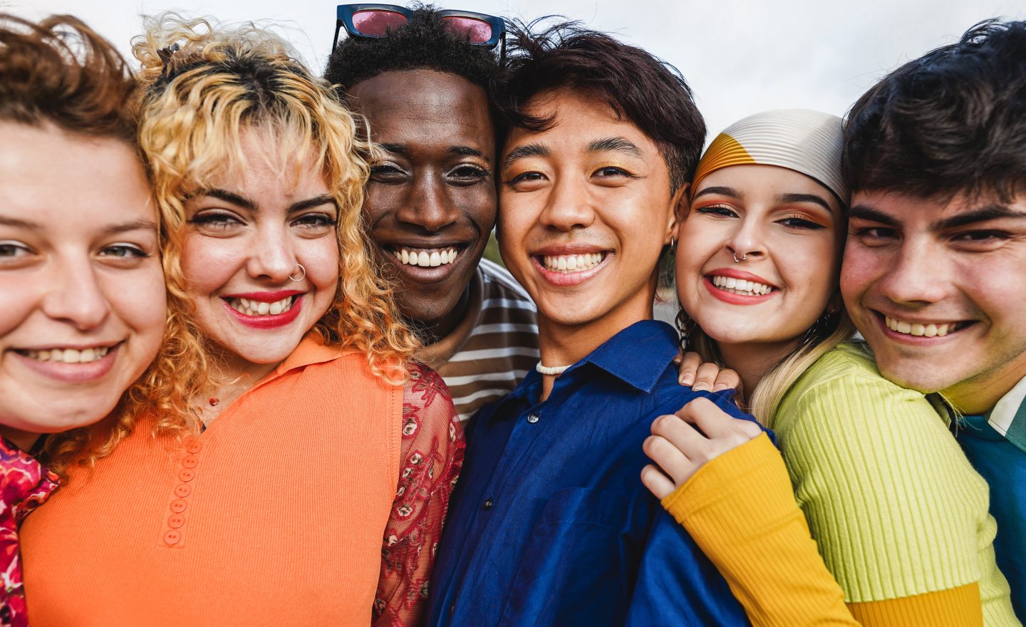 Young diverse people having fun outdoor laughing together – Focus on two center man faces