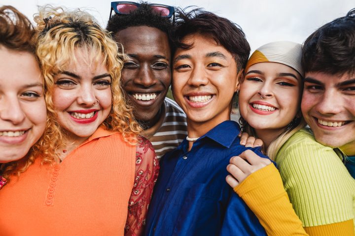 Young diverse people having fun outdoor laughing together – Focus on two center man faces