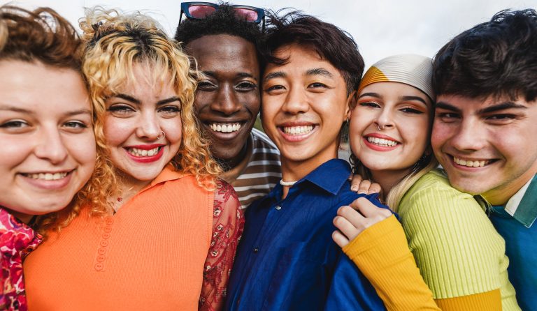 Young diverse people having fun outdoor laughing together – Focus on two center man faces