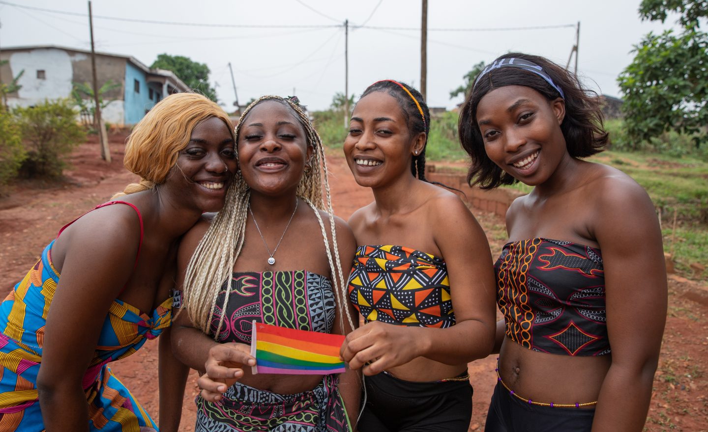 Group of smiling African lesbian girls together with the rainbow flag get together, LGBTQ + in africa